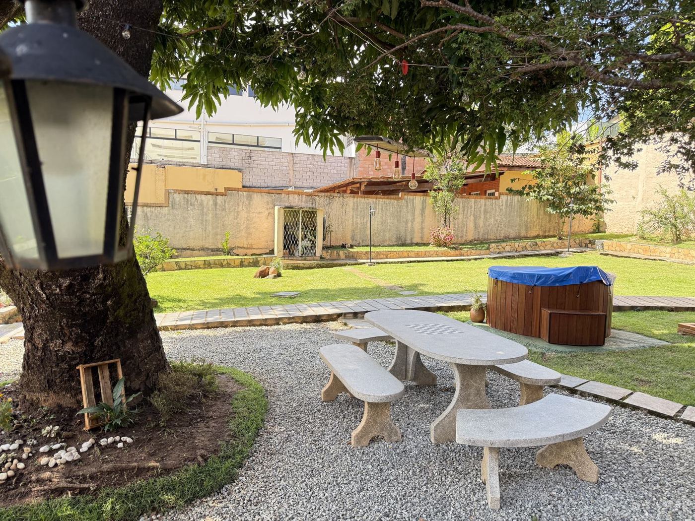 Área gourmet do Casarão com mesa de pedra sob a mangueira e spa de hidromassagem