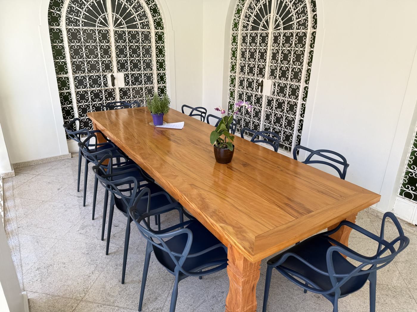Mesa de jantar de madeira para dez lugares diante das portas em arco do salão